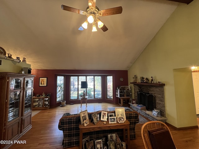 living room featuring ceiling fan, a fireplace, wood-type flooring, and lofted ceiling