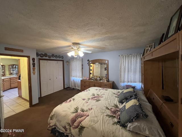 tiled bedroom with ceiling fan, ensuite bathroom, a textured ceiling, and a closet