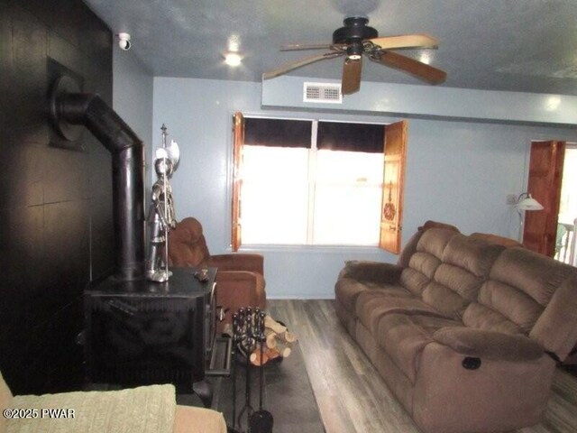 102 Yvonne Ct, Dingmans Ferry, PA 18328 - living area featuring ceiling fan, visible vents, wood finished floors, and a wood stove