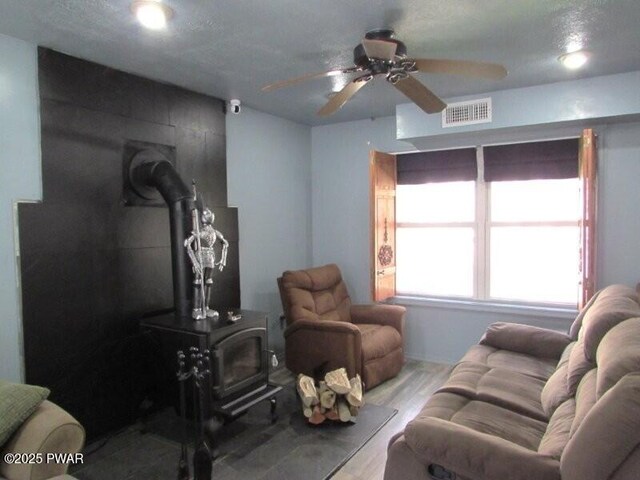 102 Yvonne Ct, Dingmans Ferry, PA 18328 - living room with a ceiling fan, a wood stove, wood finished floors, and visible vents