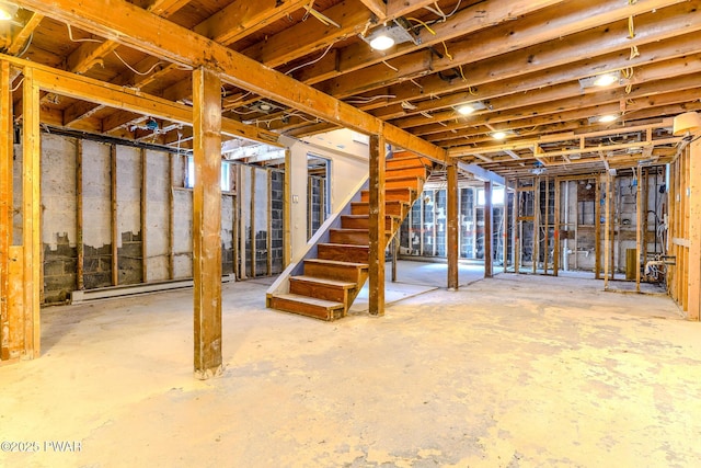 unfinished basement featuring stairs and a baseboard radiator