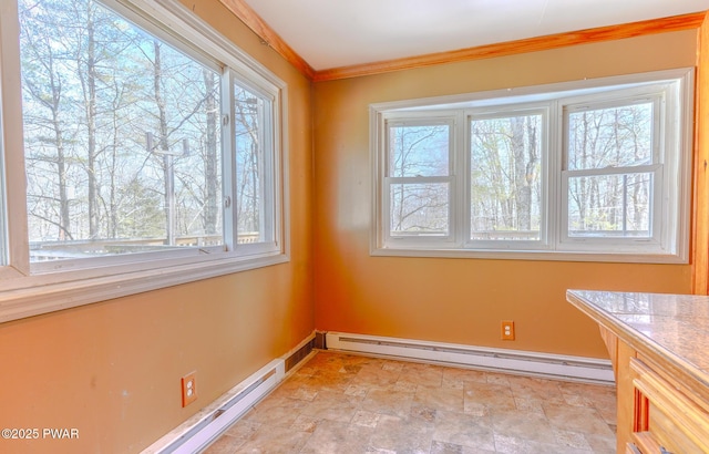 unfurnished dining area with a baseboard heating unit, stone finish floor, ornamental molding, and baseboards