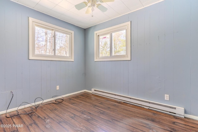 spare room featuring a baseboard radiator, baseboards, ceiling fan, and wood finished floors