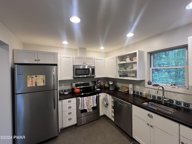 kitchen with dark tile patterned floors, sink, white cabinets, tasteful backsplash, and stainless steel appliances