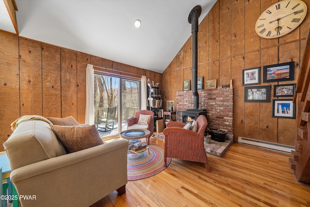 105 Tupelo Dr, Lords Valley, PA 18428 - living room with baseboard heating, a wood stove, wood walls, wood finished floors, and high vaulted ceiling