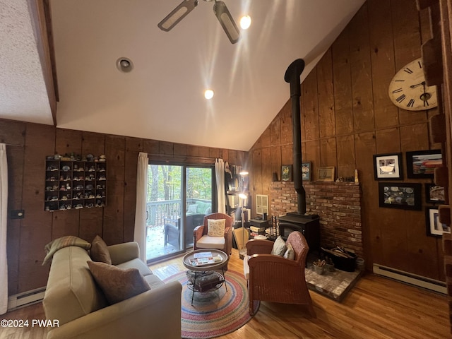 living room with a wood stove, wooden walls, baseboard heating, and hardwood / wood-style flooring