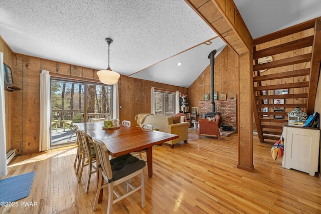 105 Tupelo Dr, Lords Valley, PA 18428 - dining area featuring a wood stove, wooden walls, light wood finished floors, a textured ceiling, and a baseboard radiator