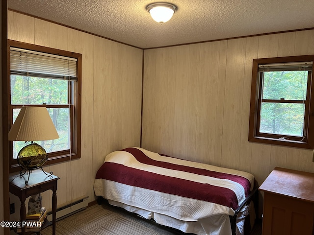 bedroom with a textured ceiling, a baseboard radiator, multiple windows, and wooden walls