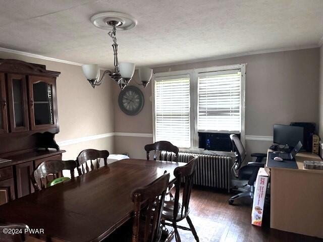 dining room featuring radiator, dark hardwood / wood-style flooring, ornamental molding, and a notable chandelier