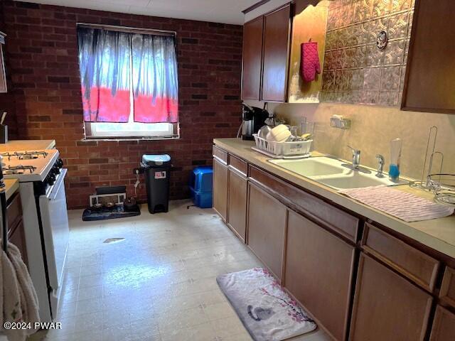 kitchen with sink, brick wall, and white stove