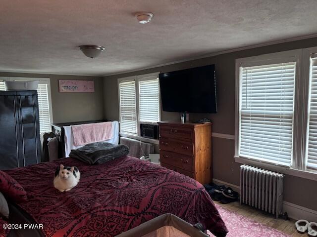 bedroom featuring radiator heating unit and a textured ceiling