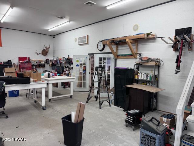 interior space with a workshop area, concrete flooring, and a wall unit AC