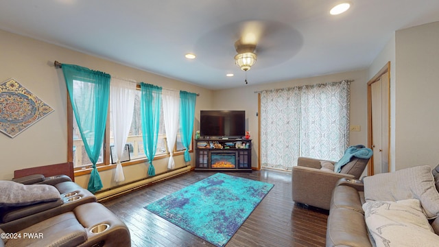 living room featuring ceiling fan, a fireplace, a baseboard radiator, and dark hardwood / wood-style floors