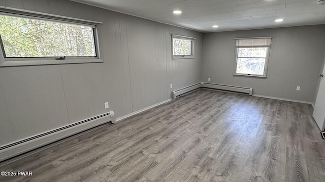 unfurnished room featuring light hardwood / wood-style floors and a baseboard heating unit