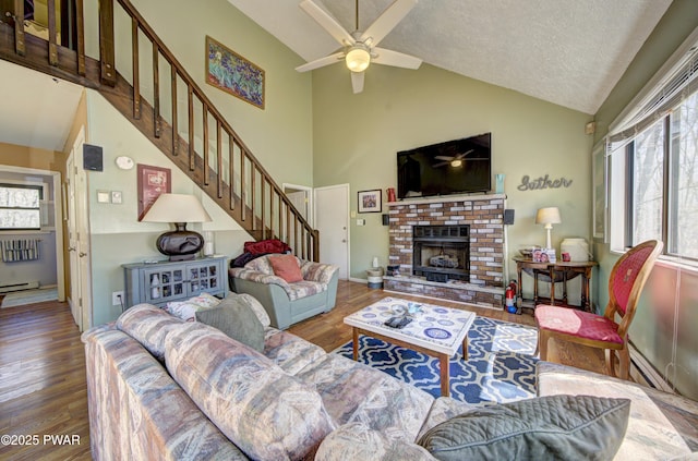 living room featuring ceiling fan, a fireplace, stairway, and a healthy amount of sunlight
