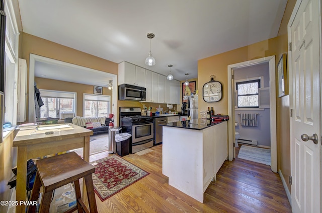 kitchen featuring a baseboard radiator, light wood-style flooring, white cabinetry, and appliances with stainless steel finishes