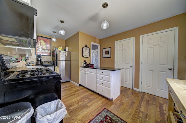 kitchen with white cabinets, light wood-type flooring, freestanding refrigerator, gas range oven, and hanging light fixtures