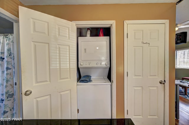 clothes washing area with stacked washer and dryer and laundry area