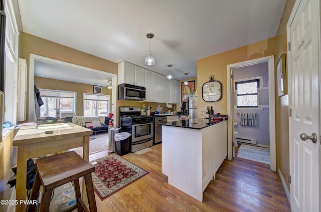 kitchen featuring a baseboard heating unit, light wood-type flooring, a peninsula, appliances with stainless steel finishes, and white cabinetry