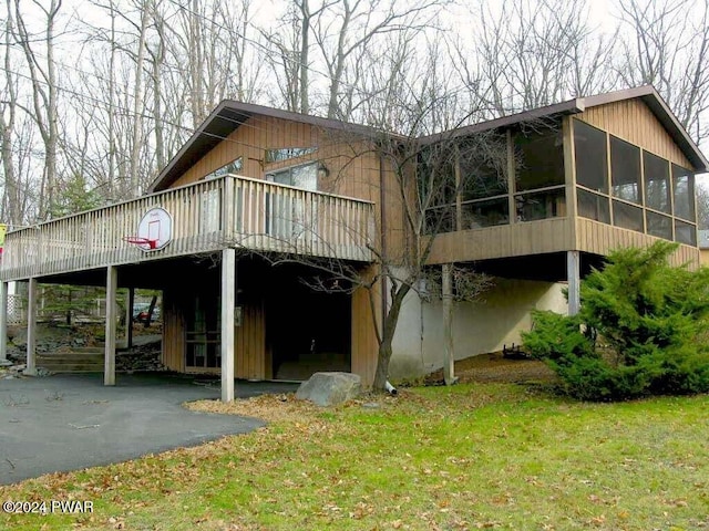 back of property with a sunroom and a lawn