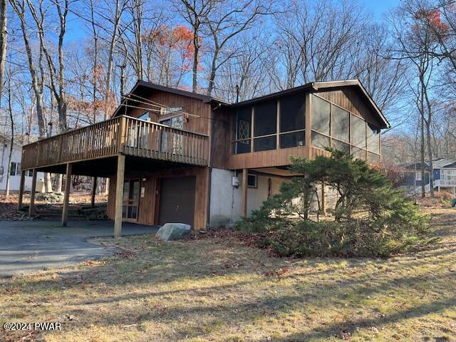 exterior space featuring a wooden deck, a sunroom, and a garage