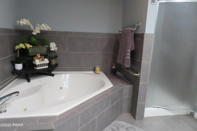 bathroom featuring tile patterned flooring, a shower stall, and a tub with jets