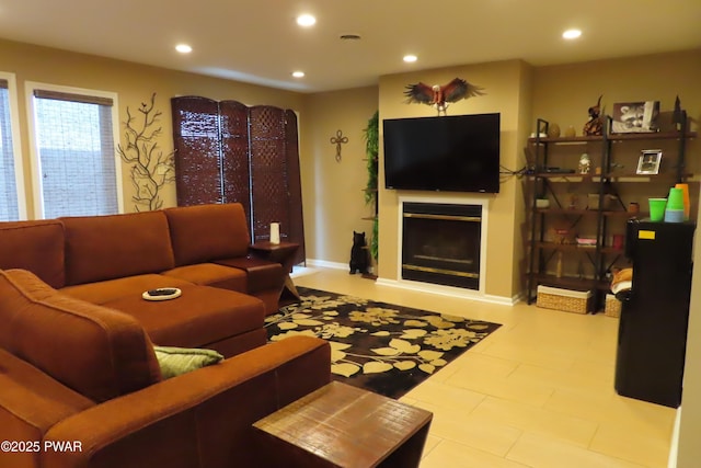 living area featuring baseboards, a glass covered fireplace, and recessed lighting