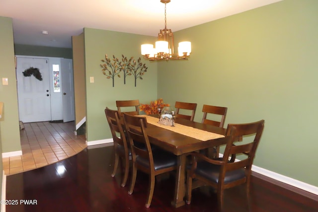 dining room with baseboards, a notable chandelier, and wood finished floors