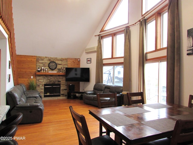 169 N Lake Dr, Dingmans Ferry, PA 18328 - dining space with high vaulted ceiling, a fireplace, light wood finished floors, and wood walls