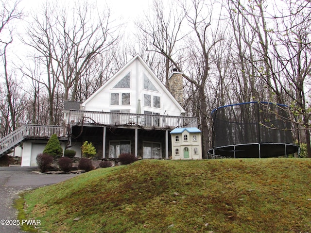 169 N Lake Dr, Dingmans Ferry, PA 18328 - chalet / cabin with a trampoline, a front yard, a deck, and a chimney