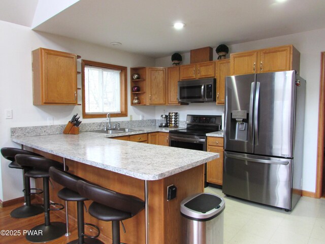169 N Lake Dr, Dingmans Ferry, PA 18328 - kitchen with a kitchen bar, a peninsula, light countertops, a sink, and stainless steel appliances