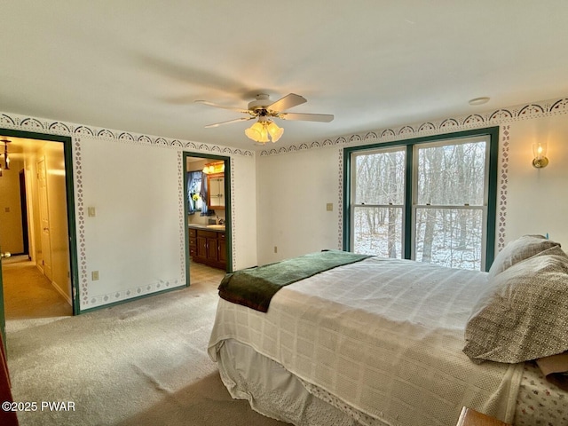 bedroom featuring ceiling fan, ensuite bath, and light carpet