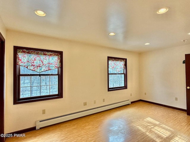 unfurnished room featuring light wood-type flooring and baseboard heating