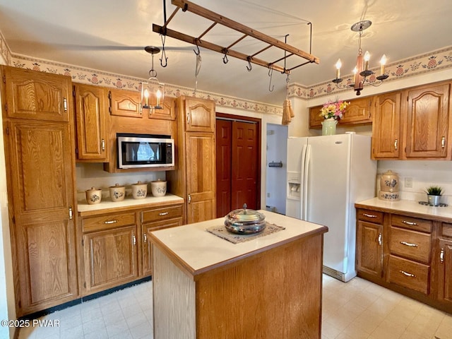 kitchen featuring white refrigerator with ice dispenser, a center island, and decorative light fixtures