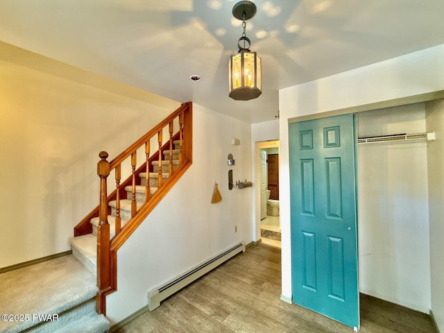 staircase with a baseboard heating unit and hardwood / wood-style flooring