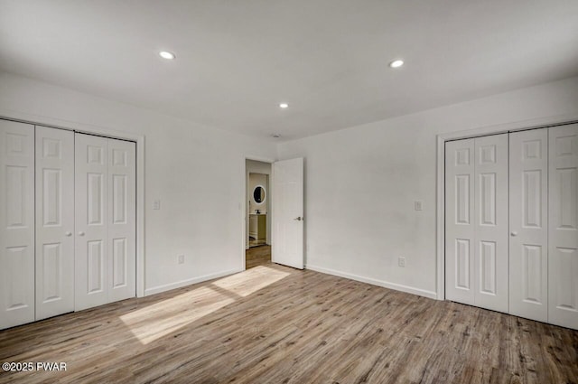 unfurnished bedroom featuring light hardwood / wood-style floors and multiple closets