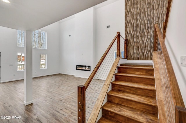 stairway featuring hardwood / wood-style floors and a towering ceiling