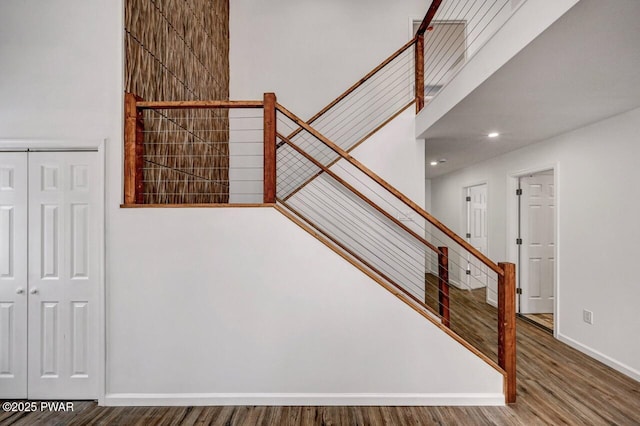 stairway with a high ceiling and hardwood / wood-style floors