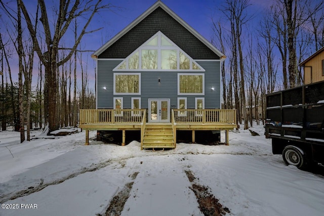 snow covered back of property featuring a deck