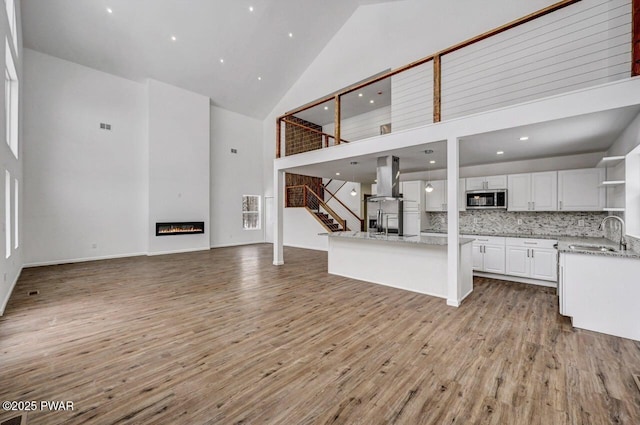 kitchen with sink, high vaulted ceiling, appliances with stainless steel finishes, decorative backsplash, and white cabinets