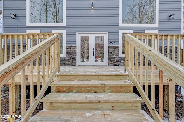 property entrance featuring a wooden deck, french doors, and stone siding