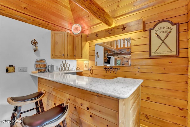 210 Fawn Lake Dr, Hawley, PA 18428 - kitchen featuring a wood ceiling with exposed beams, a peninsula, wood walls, light stone countertops, and a breakfast bar