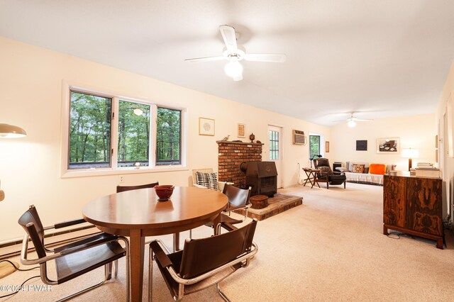 dining space featuring ceiling fan, a wood stove, and light carpet