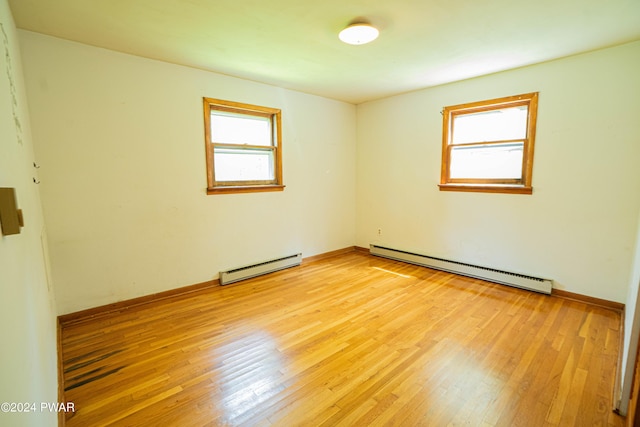 unfurnished room featuring a baseboard radiator, a healthy amount of sunlight, and light hardwood / wood-style floors