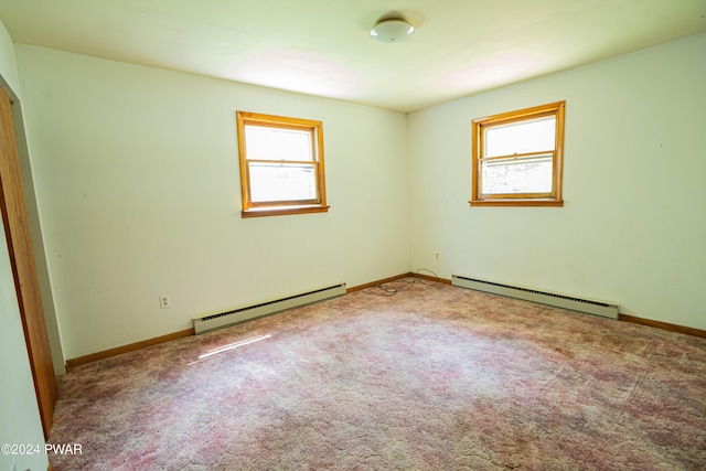 carpeted spare room with a baseboard heating unit