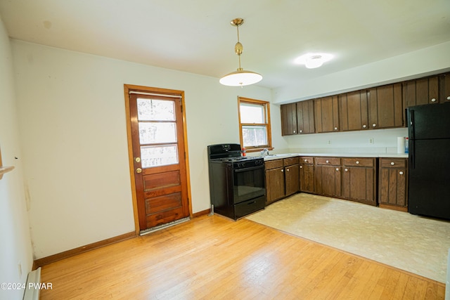 kitchen featuring black appliances, dark brown cabinets, light wood-type flooring, and hanging light fixtures