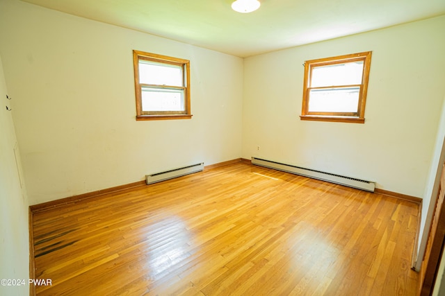 spare room with light wood-type flooring and a baseboard heating unit