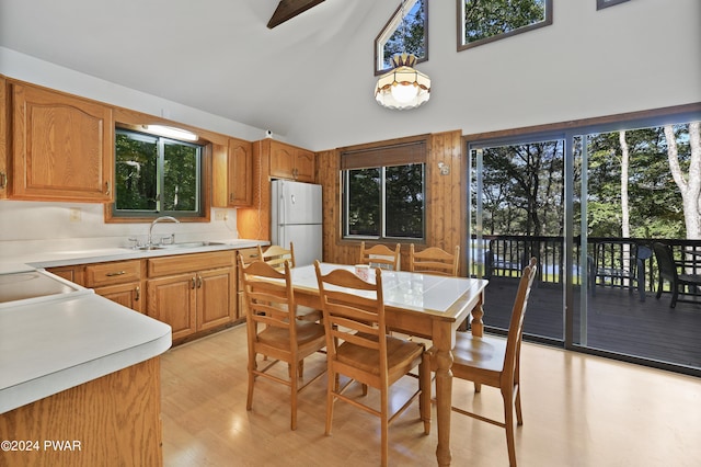 dining space with beamed ceiling, sink, high vaulted ceiling, and light hardwood / wood-style flooring