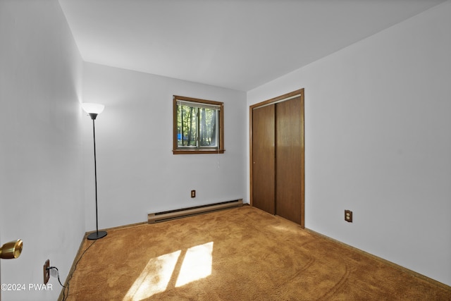 unfurnished bedroom with carpet flooring, a closet, and baseboard heating