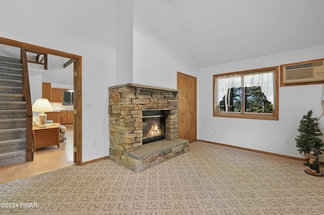 carpeted living room with an AC wall unit, a stone fireplace, and high vaulted ceiling